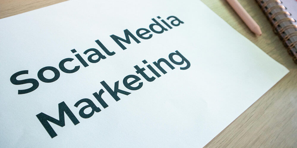 Social Media Marketing Services written on a white piece of paper on a desk next to a notebook and pen