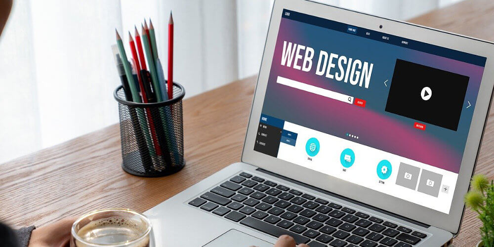 B2B Website Design and Development Agency working on a website on a laptop with a cup of coffee in their hand